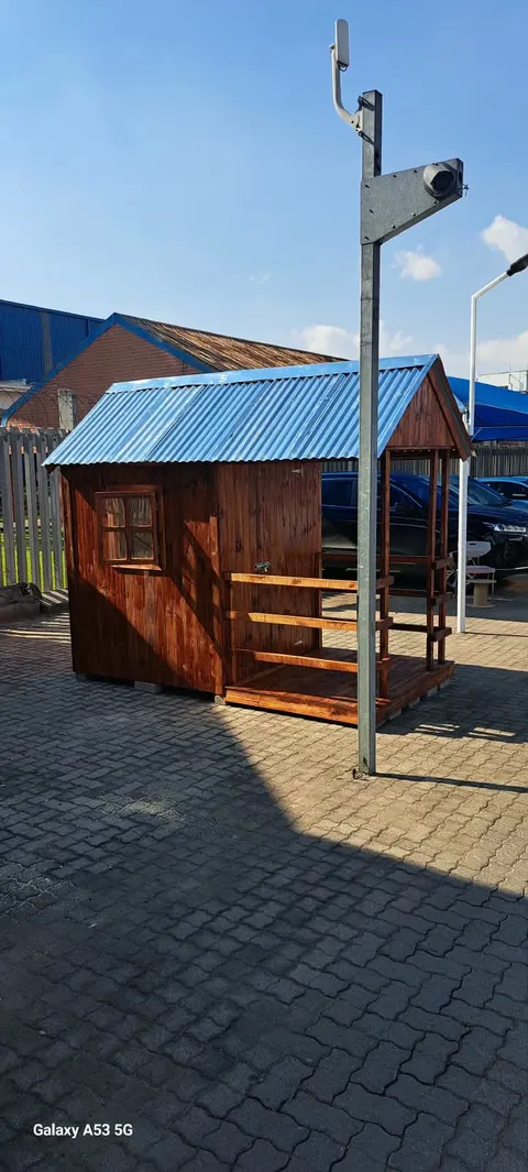 A stained timber guard hut with a blue corrugated roof, a window and a small veranda